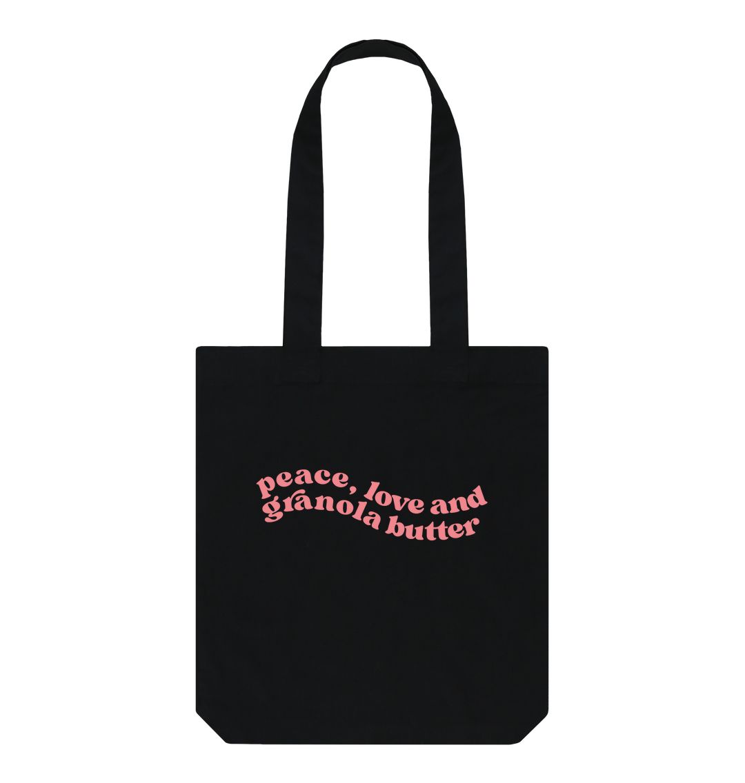 A black tote bag with pink swirly font placed in the centre of the bag, our Granola butter merchandise  