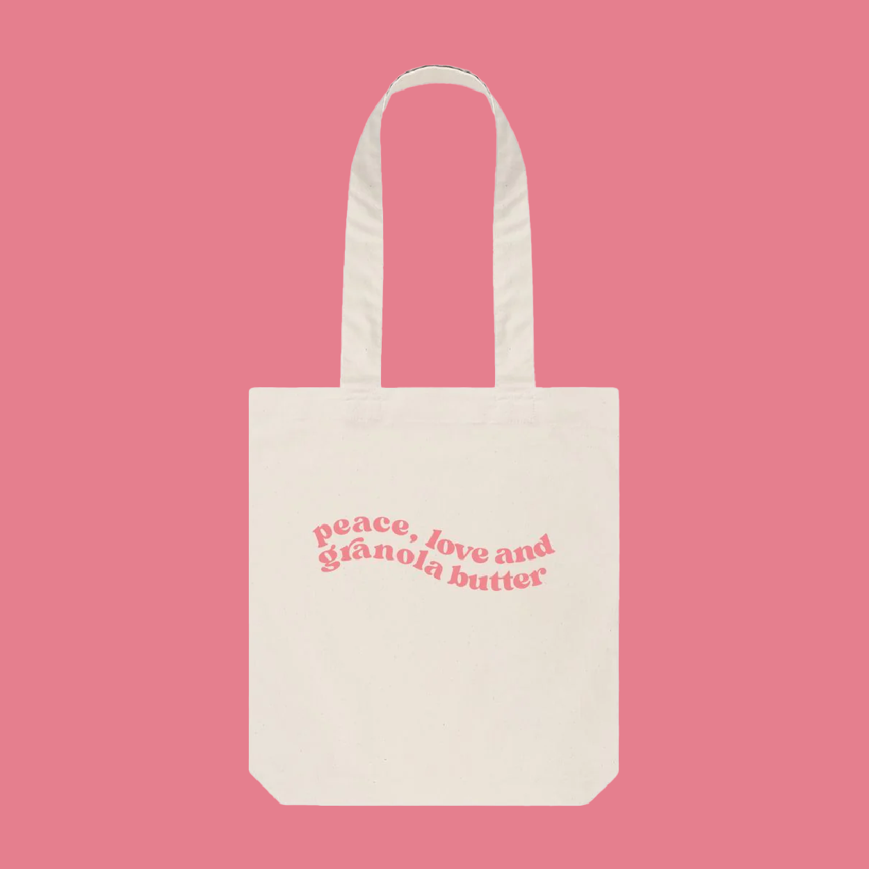 A cream tote bag with pink swirly font placed in the centre of the bag, our Granola butter merchandise  